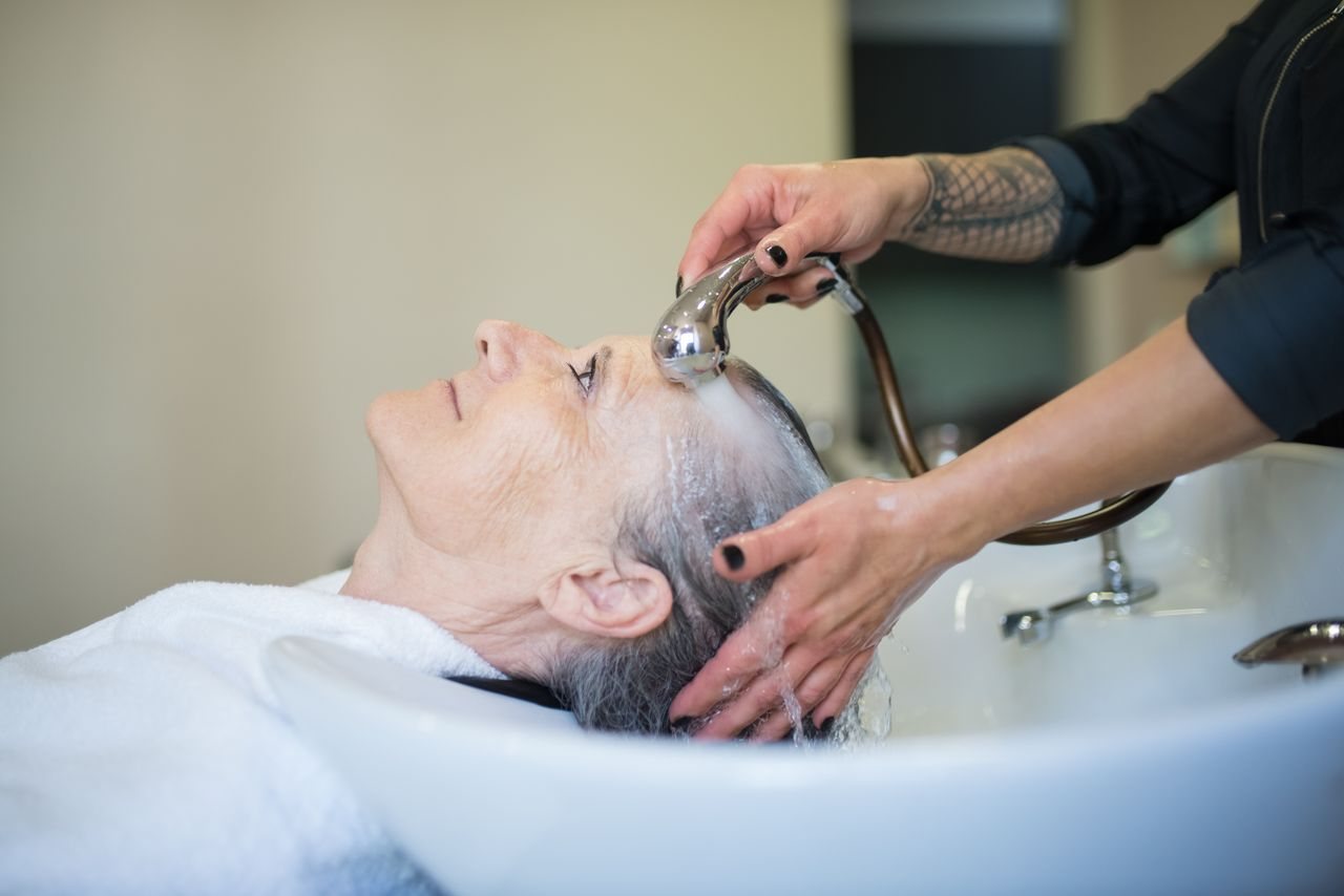 Free Elderly woman receiving a relaxing hair wash in a salon setting. Stock Photo