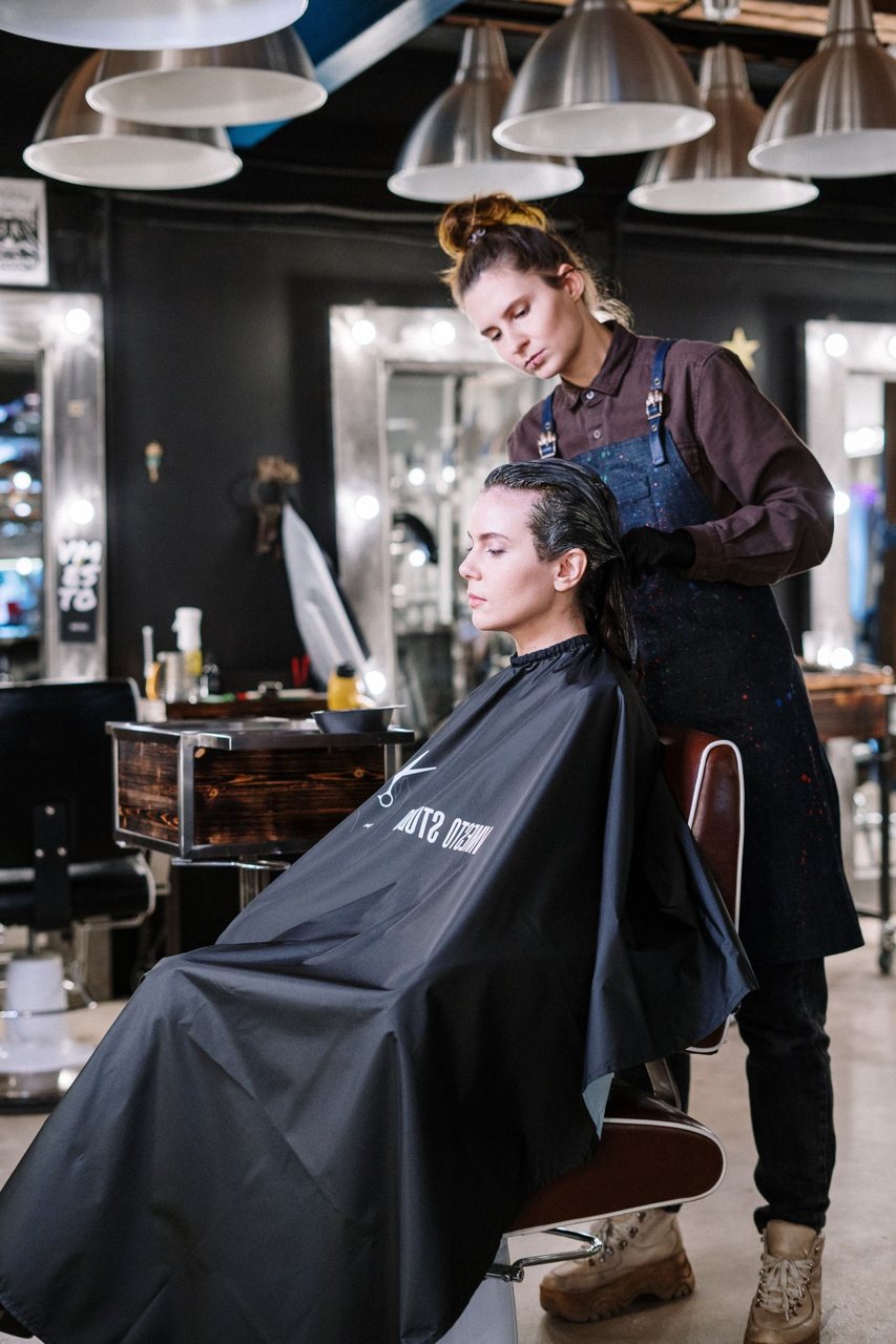 Free Hair stylist working on client's hair at a contemporary salon, providing professional hairdressing services. Stock Photo