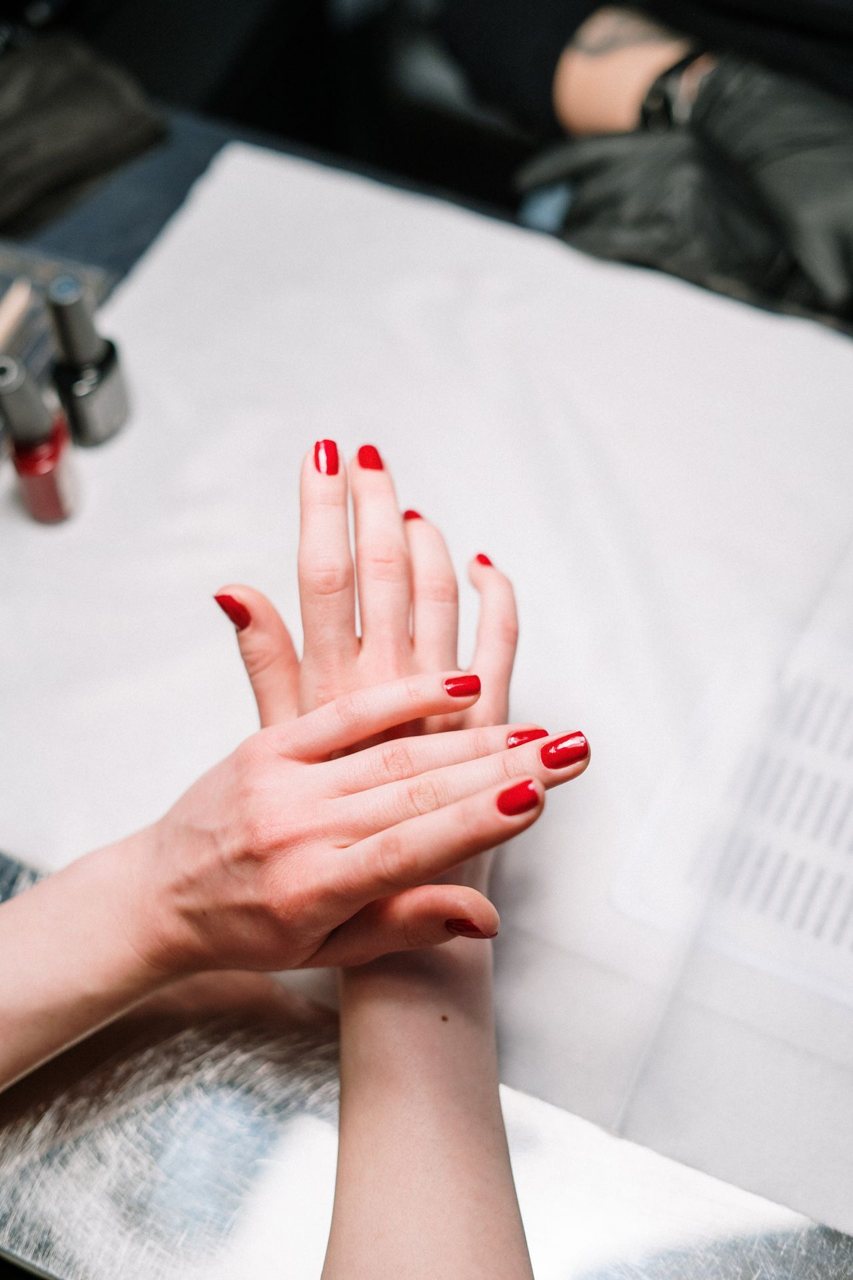 Free Professional hand treatment features a stylish red manicure at a modern nail salon. Stock Photo